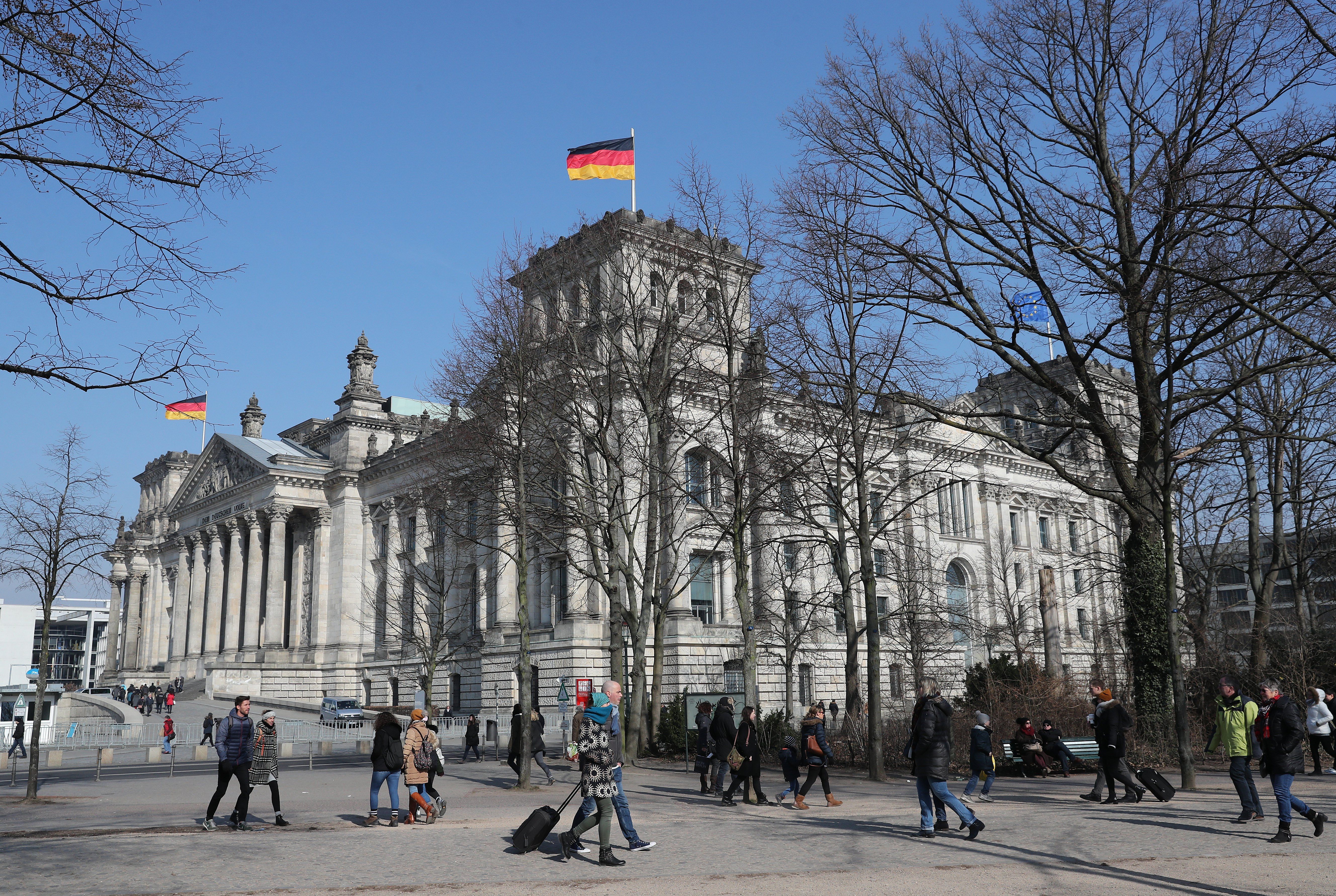 Varias personas caminan frente al edificio del Reichstag, en Berlín, el Parlamento de Alemania.