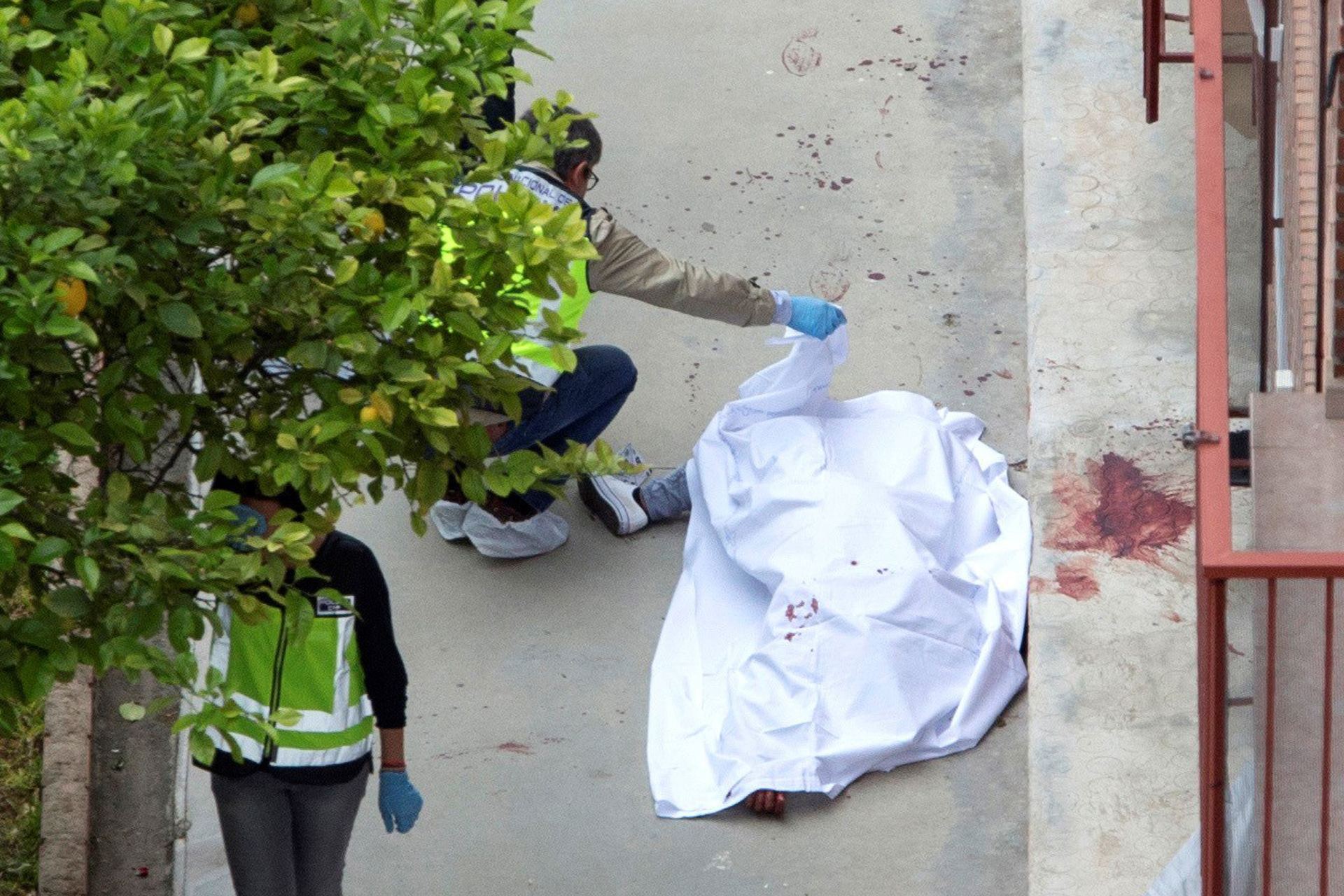 Agentes de la policía nacional examinan el cuerpo de la mujer que murió en Murcia apuñalada por su pareja.