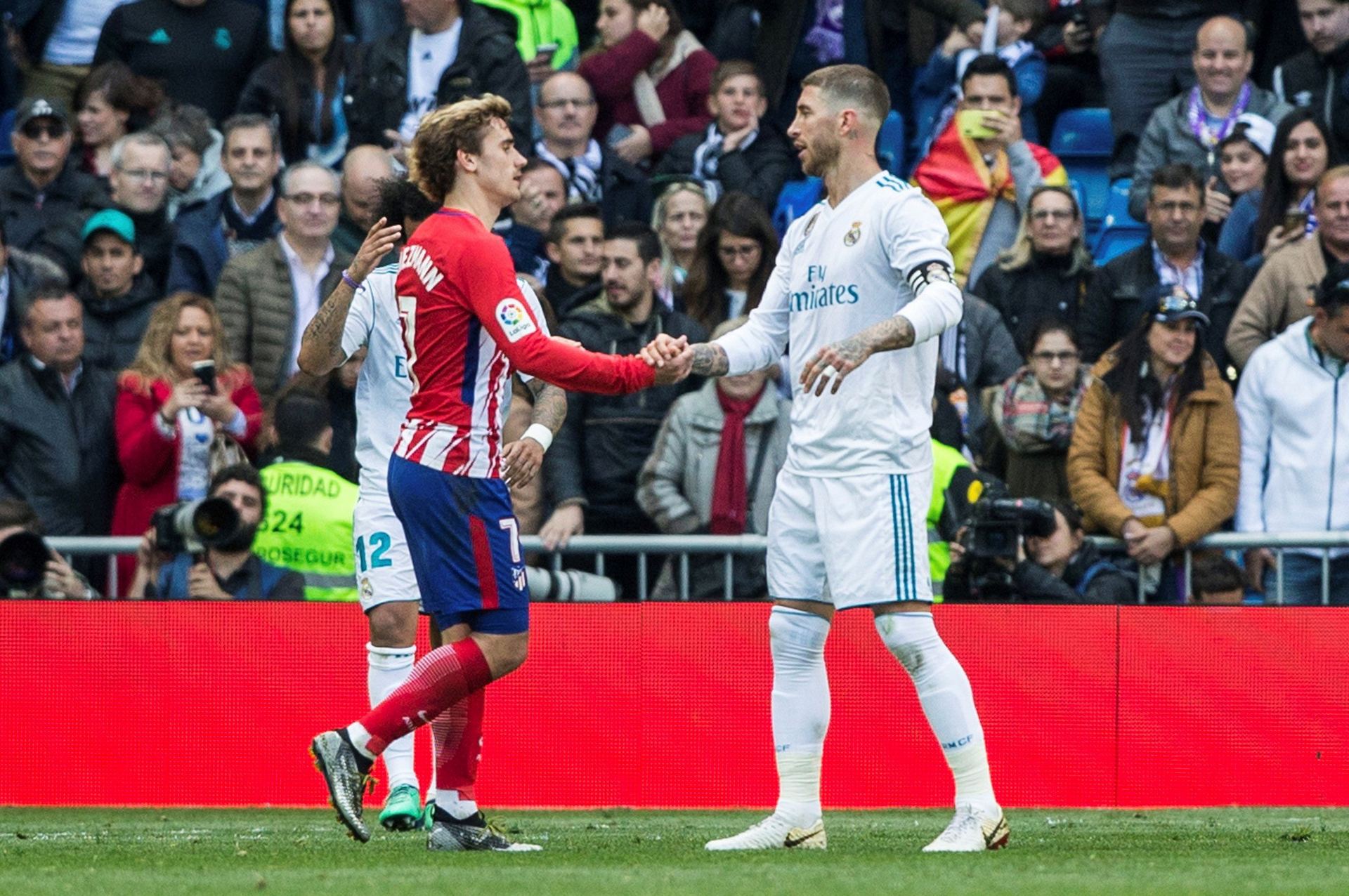 El delantero colchonero, Antoine Griezmann(i) y el defensa del Real Madrid, Sergio Ramos, se saludan al finalizar el derbi madrileño en el Bernabéu.