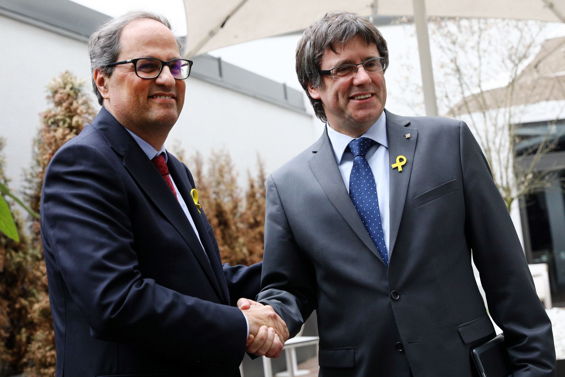 El presidente de la Generalitat, Quim Torra, estrecha la mano a su predecesor, el expresidente Carles Puigdemont.