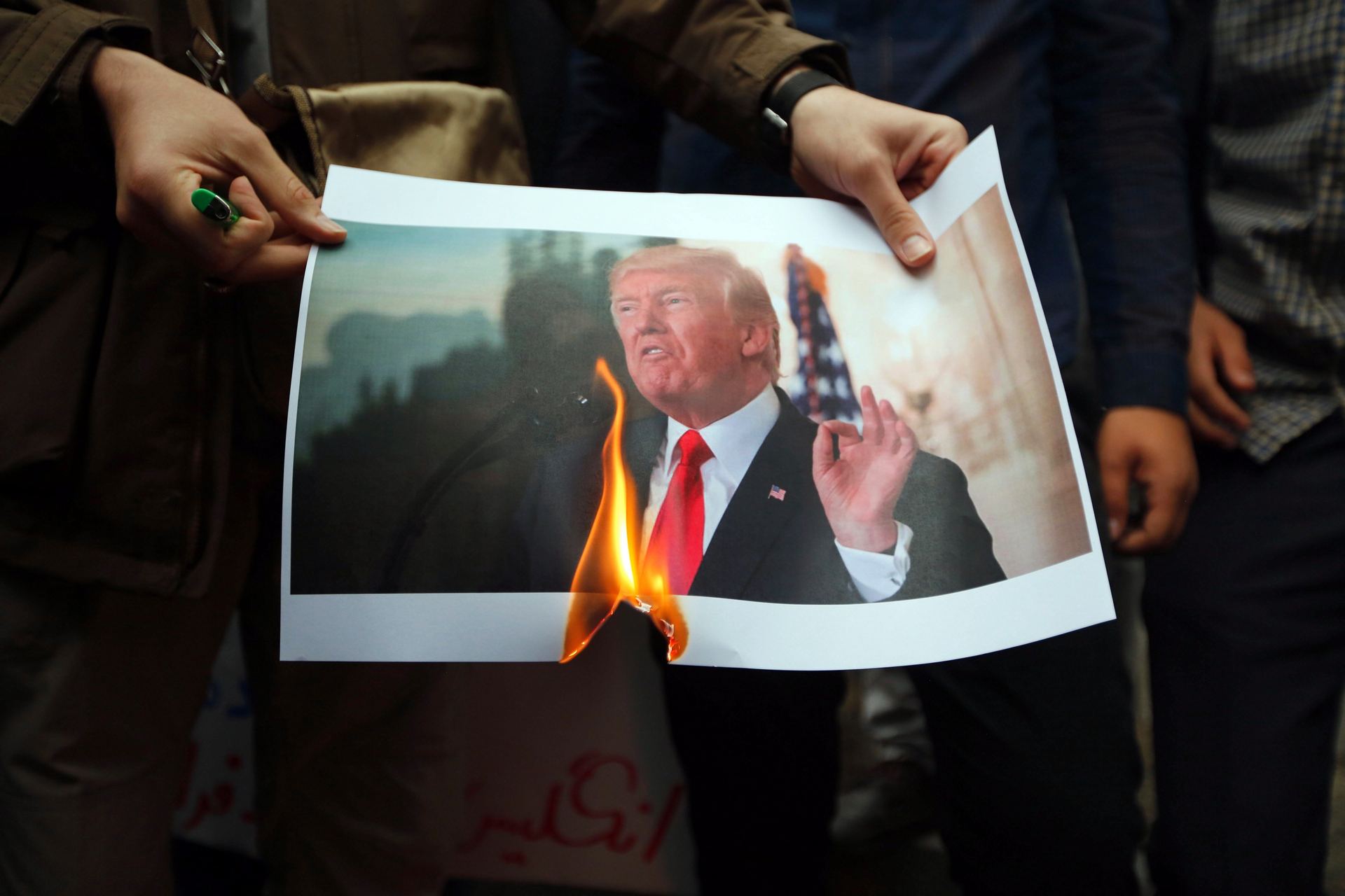 Un grupo de iraníes quema una fotografía del presidente estadounidense, Donald Trump, ayer en Teherán.