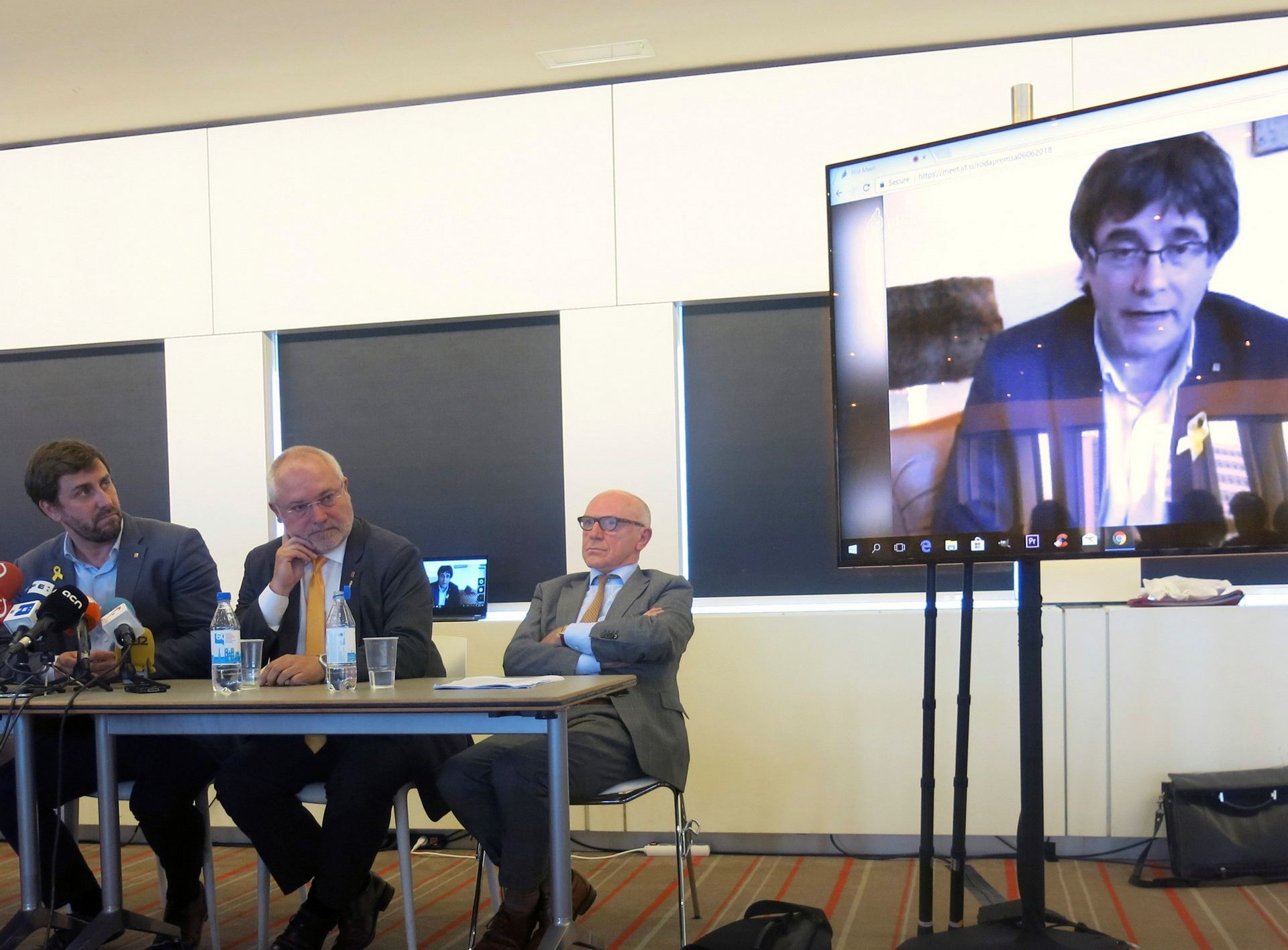 Los exconsejeros de la Generalitat huidos, Toni Comín (i) y Lluís Puig (2i) y el abogado Paul Bekaert escuchan a Puigdemont.