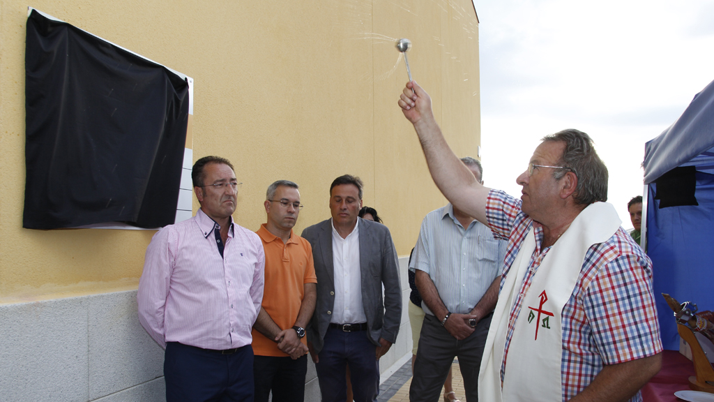 El párroco de Palazuelos bendice el nuevo edificio, antes de descubrir la placa. /NEREA LLORENTE
