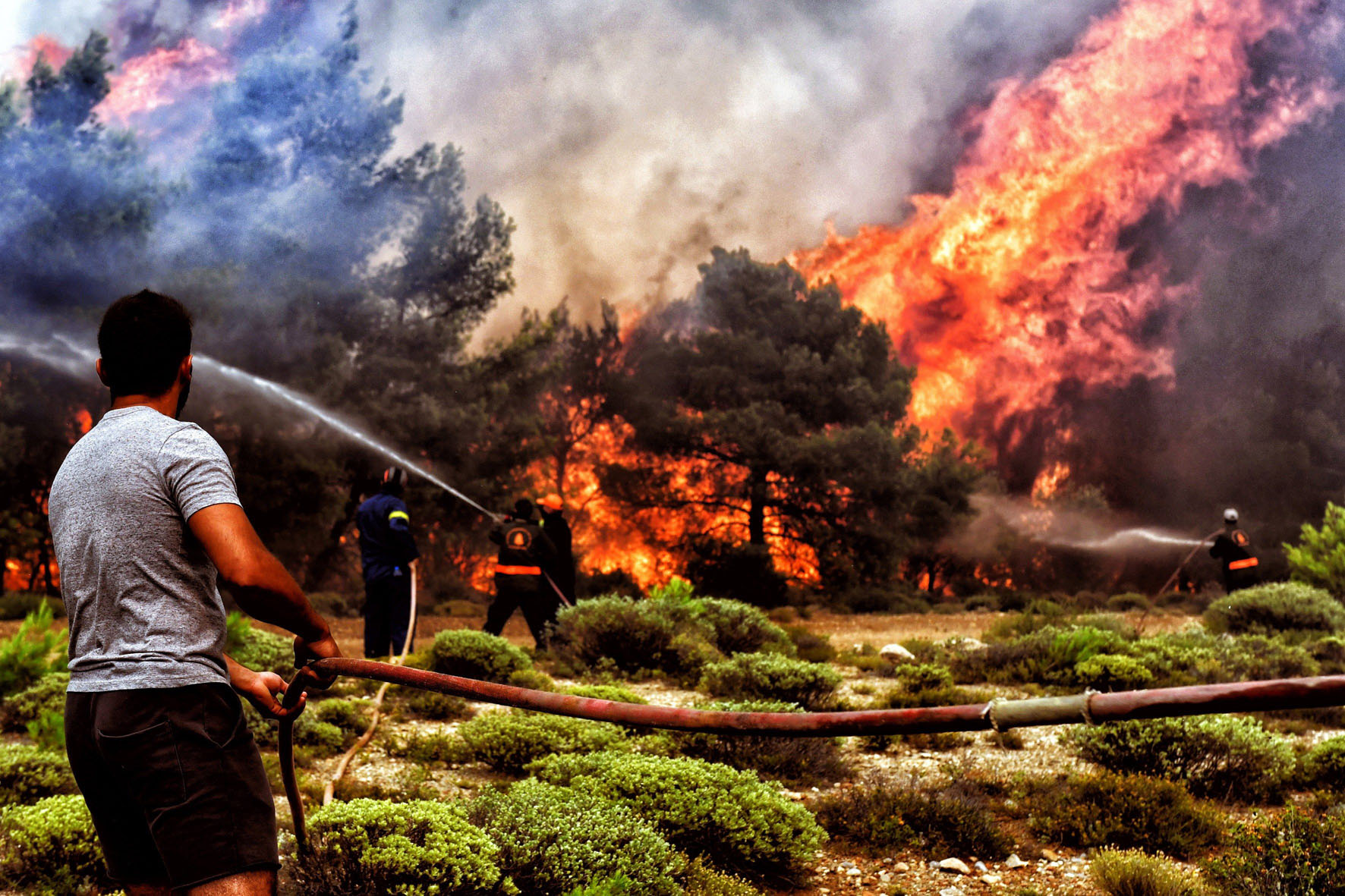 Bomberos y voluntarios luchan contra las llamas en un incendio en Verori, cerca de Loutraki.