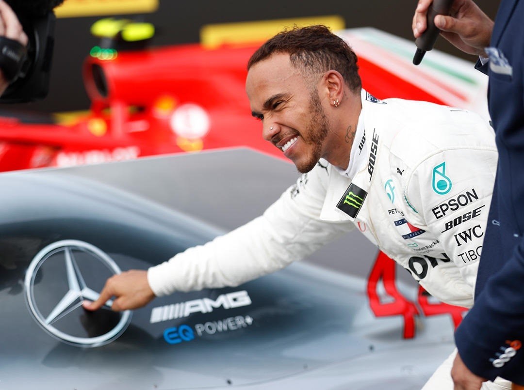 Lewis Hamilton señala el logo de Mercedes.
