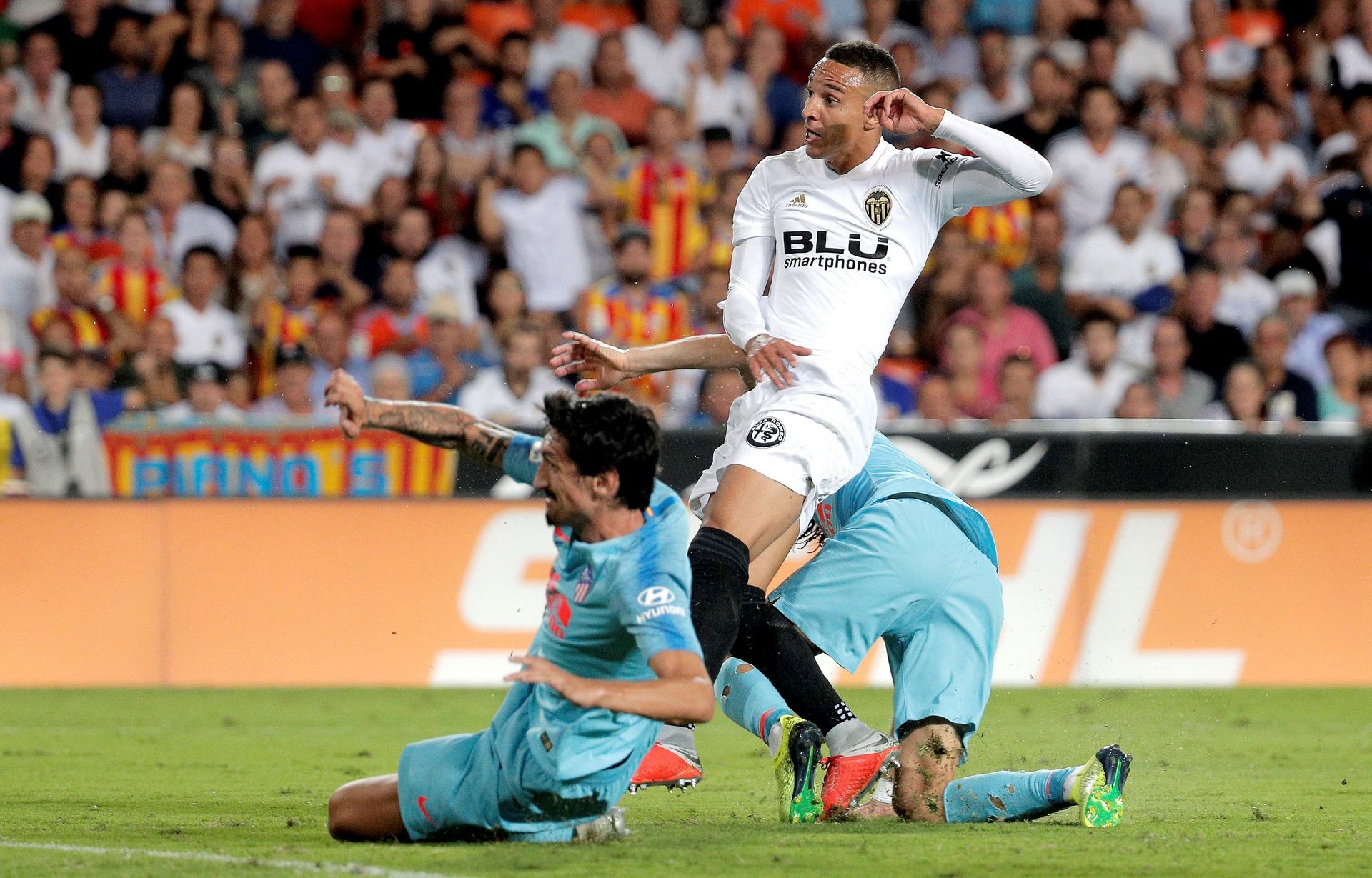 El delantero del Valencia CF Rodrigo (c), entre los atlétcicos Filipe Luis (d) y Savic, tras disparar a puerta.
