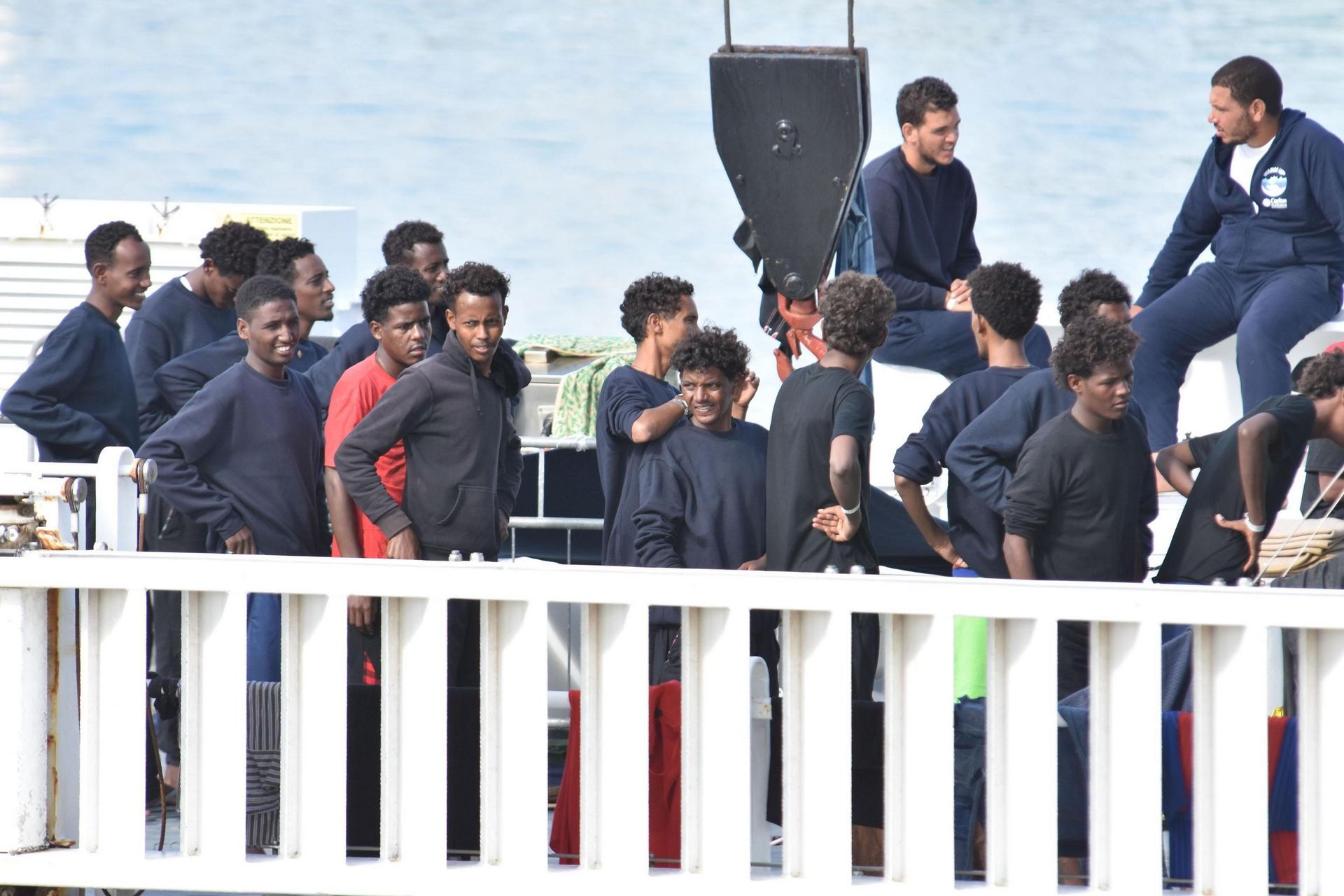 Varios migrantes aguardan a bordo de barco de los guardacostas "Diciotti" en el puerto de Catania (Italia) ayer.