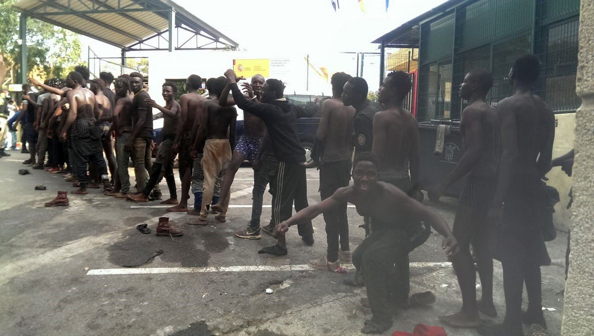 Parte del centenar de inmigrantes que han cruzado la valla de Ceuta celebra su llegada a suelo español.