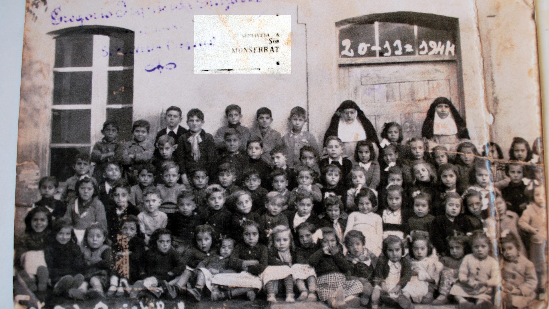 Foto de los escolares de 1944 ante la pared donde está la placa.