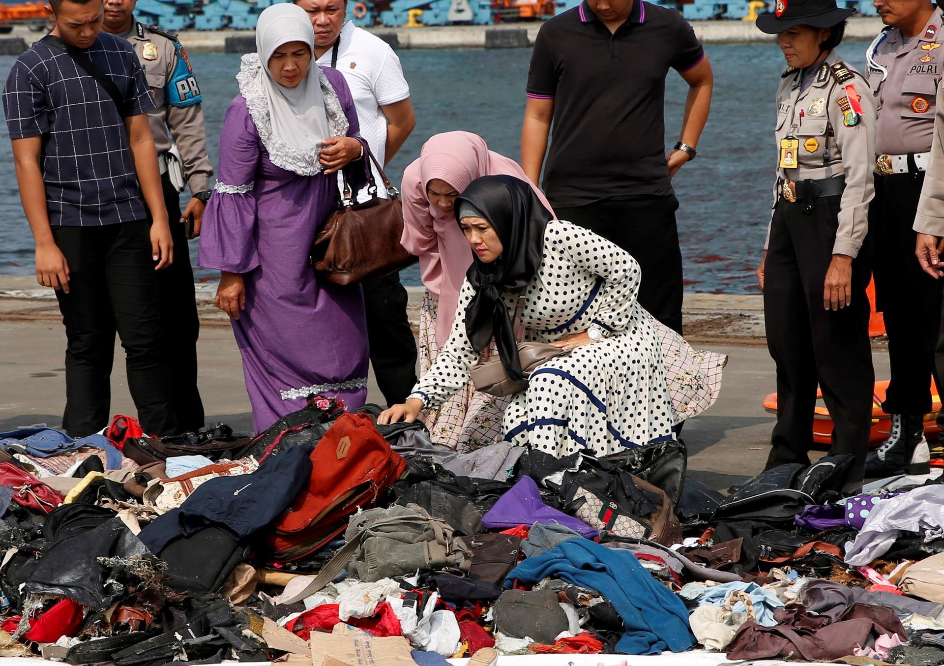 Familiares de víctimas del avión siniestrado en el mar de JAva registran los enseres recuperados.