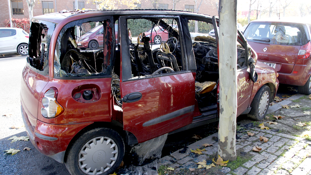 Los cristales y restos del coche incendiado todavía se encuentran en la avenida de la Constitución