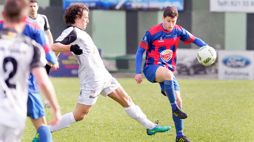 Manu despeja un balón ante la presión de un contrario durante uno de los últimos partidos que disputó la Segoviana frente al Cristo Atlético. / KAMARERO