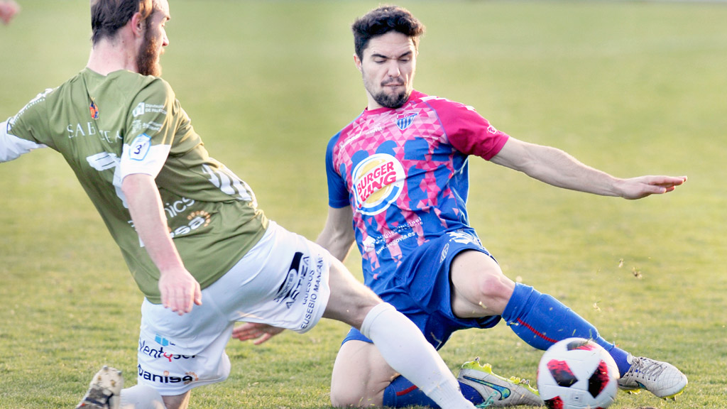 El lateral de la Gimnástica Segoviana Rubén Yubero disputa un balón a ras del suelo frente a un contrincante del Cristo Atlético. / KAMARERO