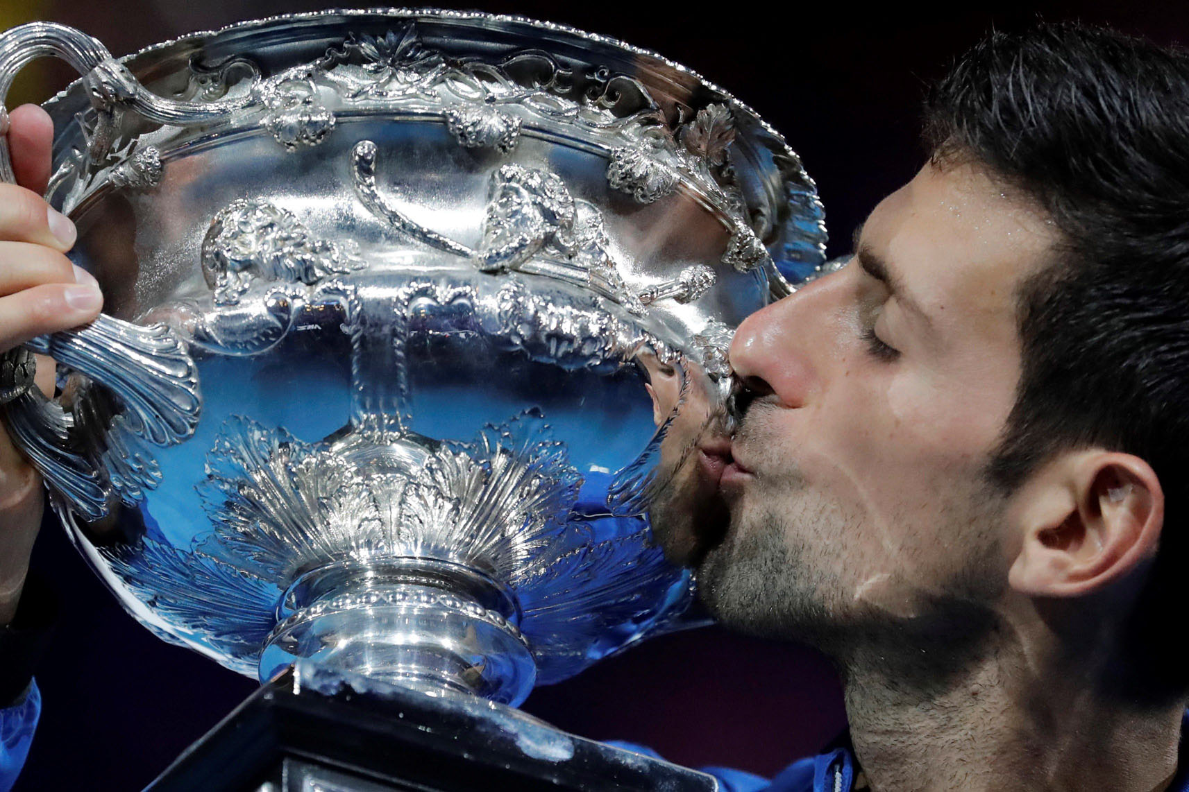 Novak Djokovic besa el trofeo de campeón del Abierto de Australia, el séptimo de su carrera, después de arrollar en la final a Rafa Nadal.