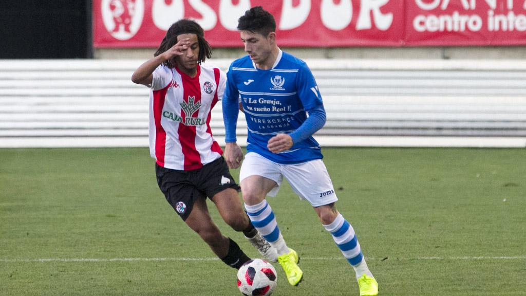 El delantero del CD La Granja Héctor Álvarez ‘Koby’ conduce el balón ante la presión del centrocampista del Zamora CF Fer. / JAVIER DE LA FUENTE CERECINOS