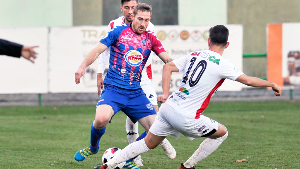 El atacante de la Gimnástica Segoviana Dani Arribas, baja para el partido de hoy, intenta marcharse de dos contrincantes. / KAMARERO