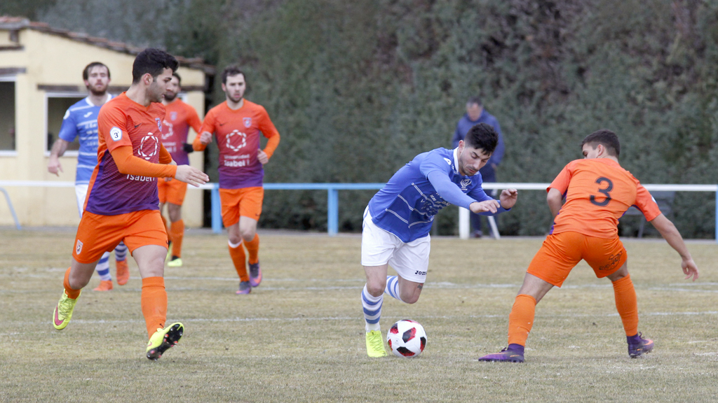 El atacante del CD La Granja Héctor Álvarez ‘Koby’ se marcha de los defensas del Burgos Promesas 2000, en el partido de ayer que acogió el campo de El Hospital. / NEREA LLORENTE