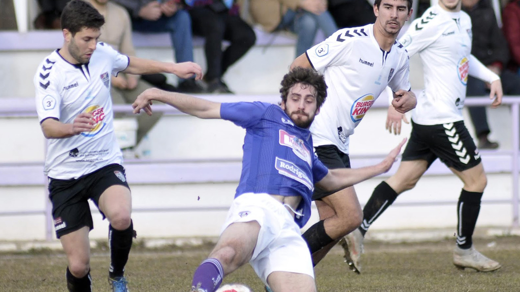 El jugador de La Bañeza contacta con el balón ante la presión de Manu, con Javi Marcos y Adrián siguiendo la jugada. / JUAN MARTIN-GIMNÁSTICA SEGOVIANA