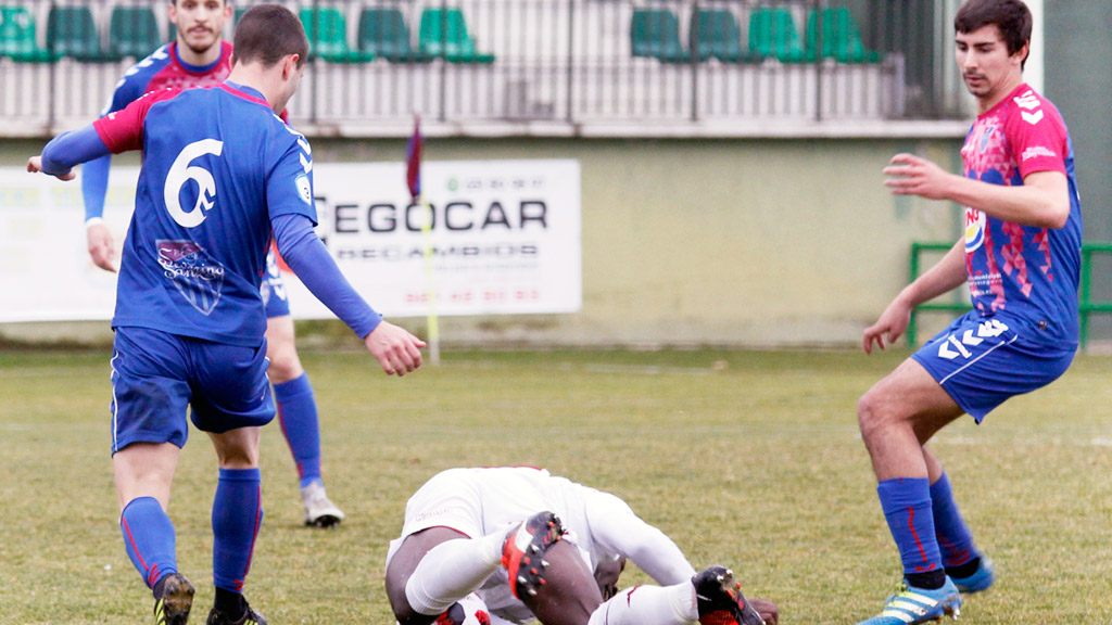 Los jugadores de la Segoviana Manu, Javi Marcos y Adrián Pérez miran a un jugador del Júpiter en el suelo. / NEREA LLORENTE