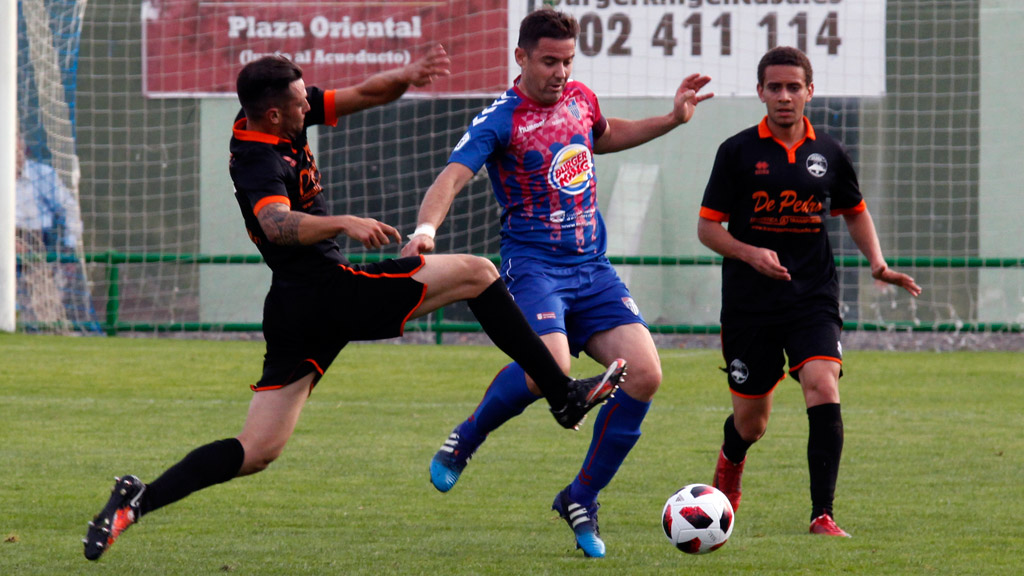 El capitán de la Gimnástica Segovia Anel intenta ganar un balón ante la entrada de un contrincante del Sporting Uxama del Burgo de Osma. / NEREA LLORENTE
