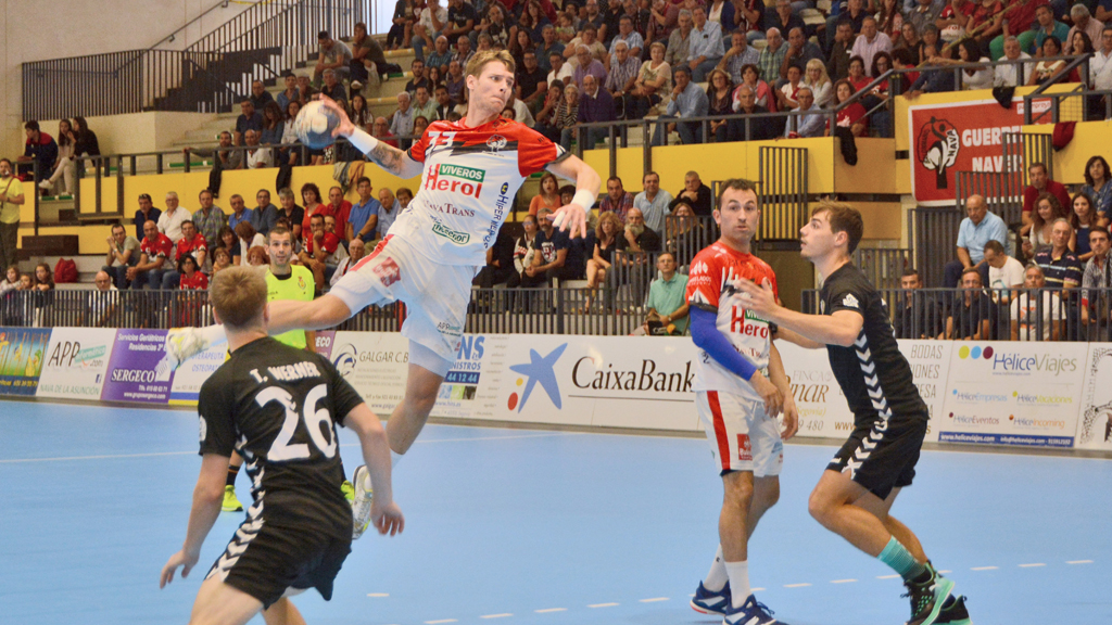 Toma Brakocevic se eleva sobre la defensa del Balonmano Santoña durante el partido de ida disputado en el pabellón de Nava de la Asunción. / AMADOR MARUGÁN