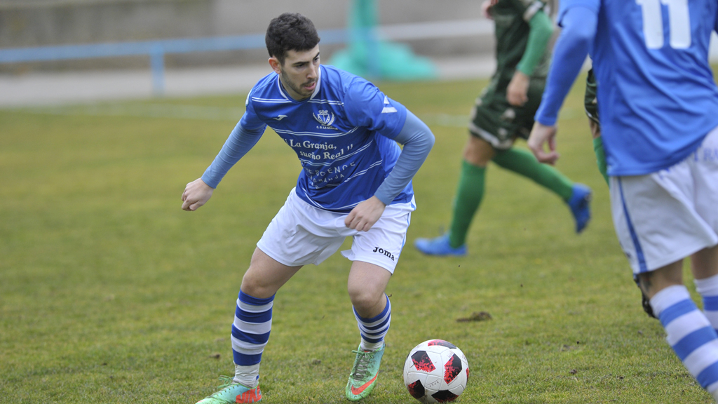 El lateral derecho del CD La Granja Alfonso Mateos conduce un balón, durante un partido. / KAMARERO
