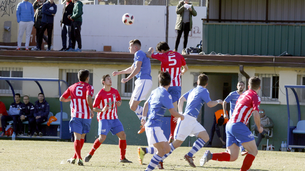 El delantero del CD La Granja Ionel Mirza disputa un balón por alto en el centro del terreno de juego con el defensa del Atlético Tordesillas Bayón / NEREA LLORENTE