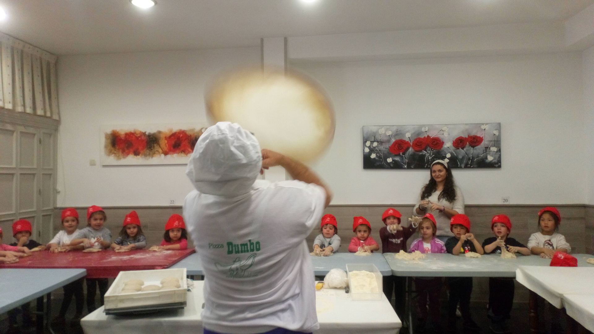 El cocinero de Pizzería Dumbo revoleando la masa de pizza ante el asombro del alumnado. / S. Sanjuán