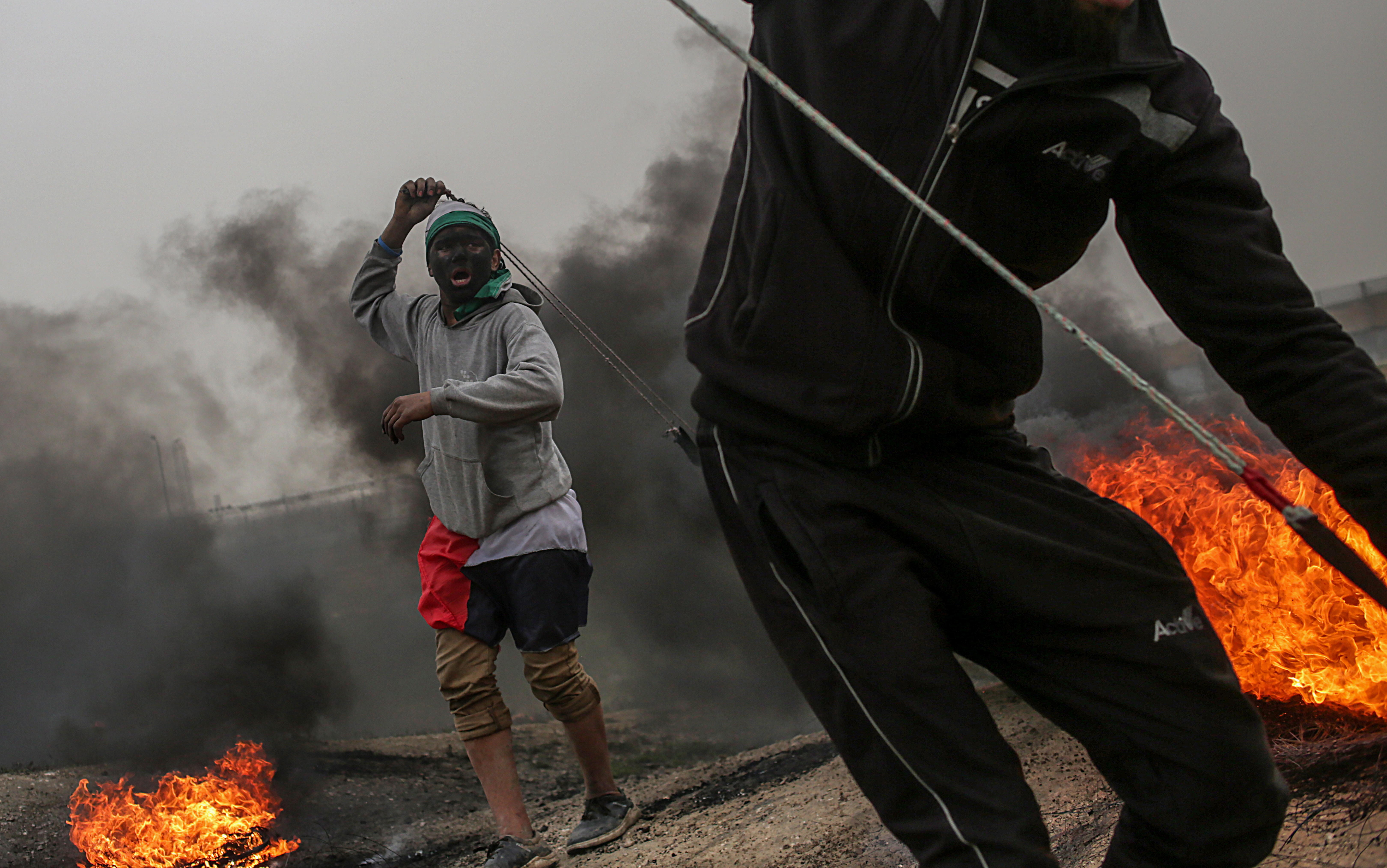 Varios manifestantes palestinos lanzan piedras contra posiciones israelíes.