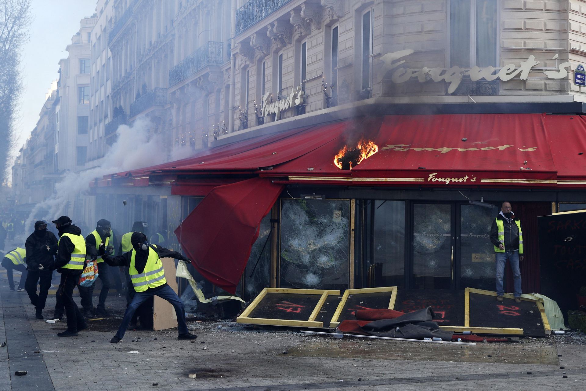Varios “chalecos amarillos” se enfrentan contra la policía antidisturbios ante el restaurante Fouquet en París.