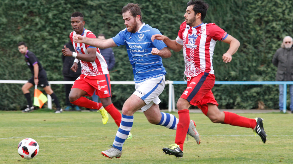 El centrocampista del CD La Granja Alfonso Berrocal intenta salir a la contra ante la presión de dos contrincantes del Atlético Bembibre. / NEREA LLORENTE