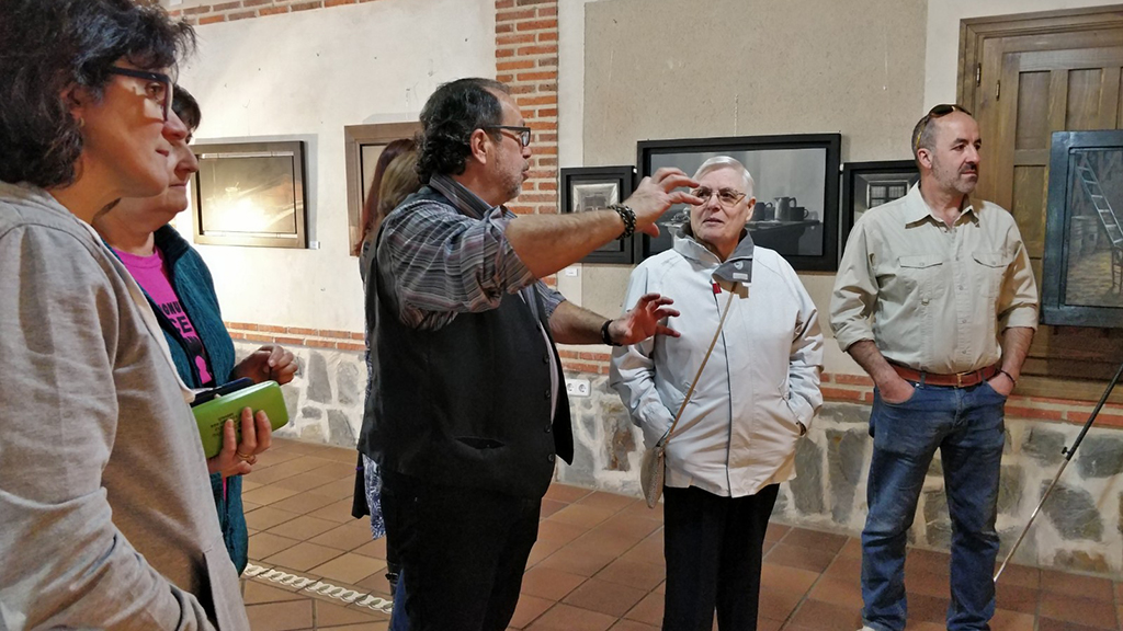 El pintor explica sus obras a los visitantes de la exposición.