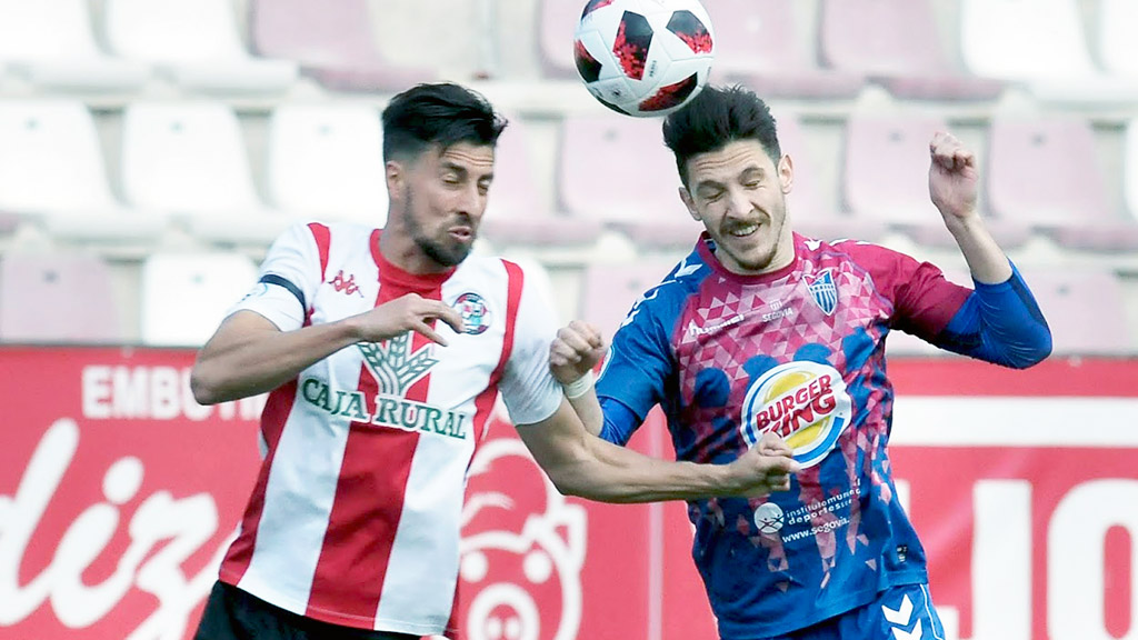 El jugador del Gimnástica Segoviana Adrián Pérez disputa un balón por alto con un contrincante del Zamora CF. / JUAN MARTÍN - LA GIMNÁSTICA