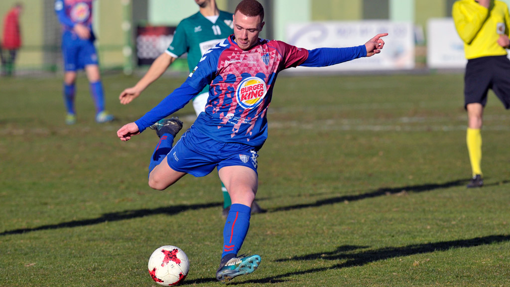 El delantero de la Gimnástica Segoviana Agus Alonso se dispone a colgar un balón desde el centro del campo, durante un partido en La Albuera. / KAMARERO