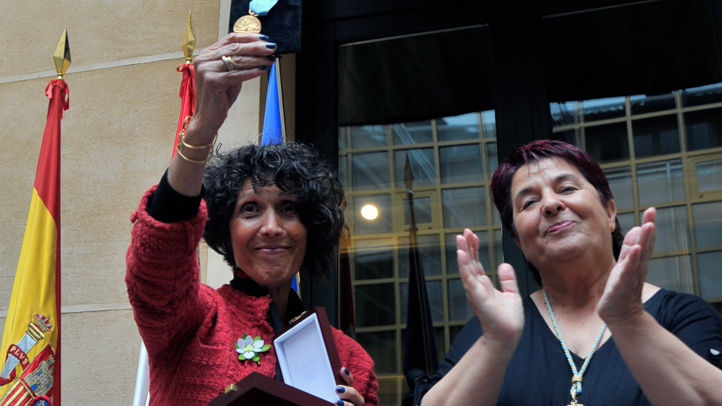 La alcaldesa aplaude mientras la presidenta provincial de la AECC muestra la Medalla de Oro de la Ciudad. / KAMARERO