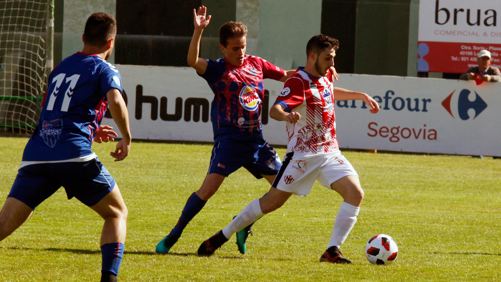 El centrocampista de la Gimnástica Segoviana Elías Hevia trata de quitar un balón a un rival del Bembibre. / NEREA LLORENTE