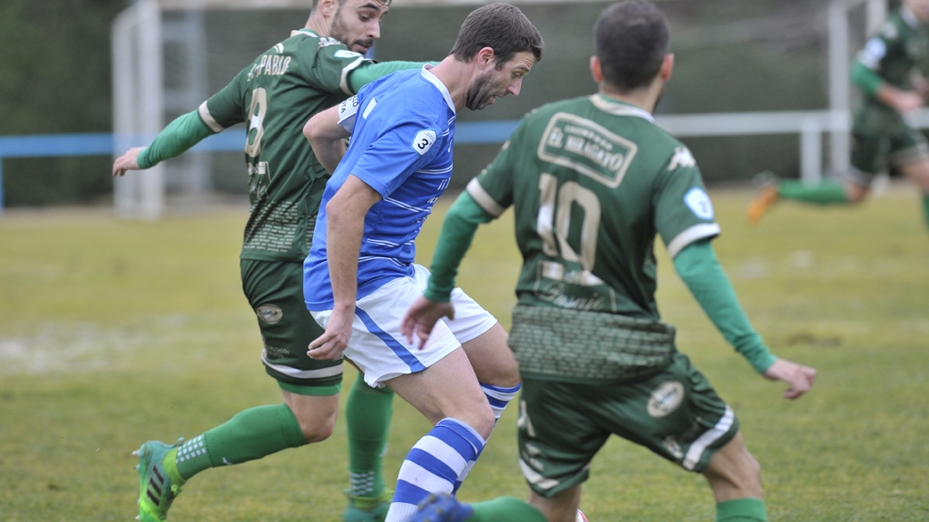 El jugador del CD La Granja Mario Zúñiga intenta marcharse de dos rivales del Astorga en la primera vuelta. / KAMARERO