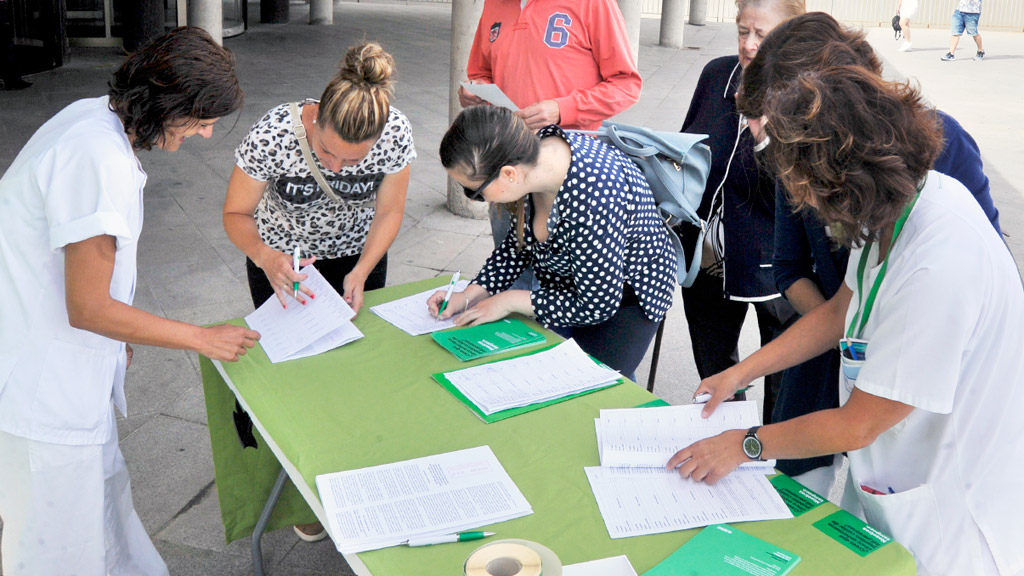 Mesa de la campaña ‘La Sanidad que merecemos. Ley de ratios enfermeras’ instalada a las puertas del Hospital General. / KAMARERO