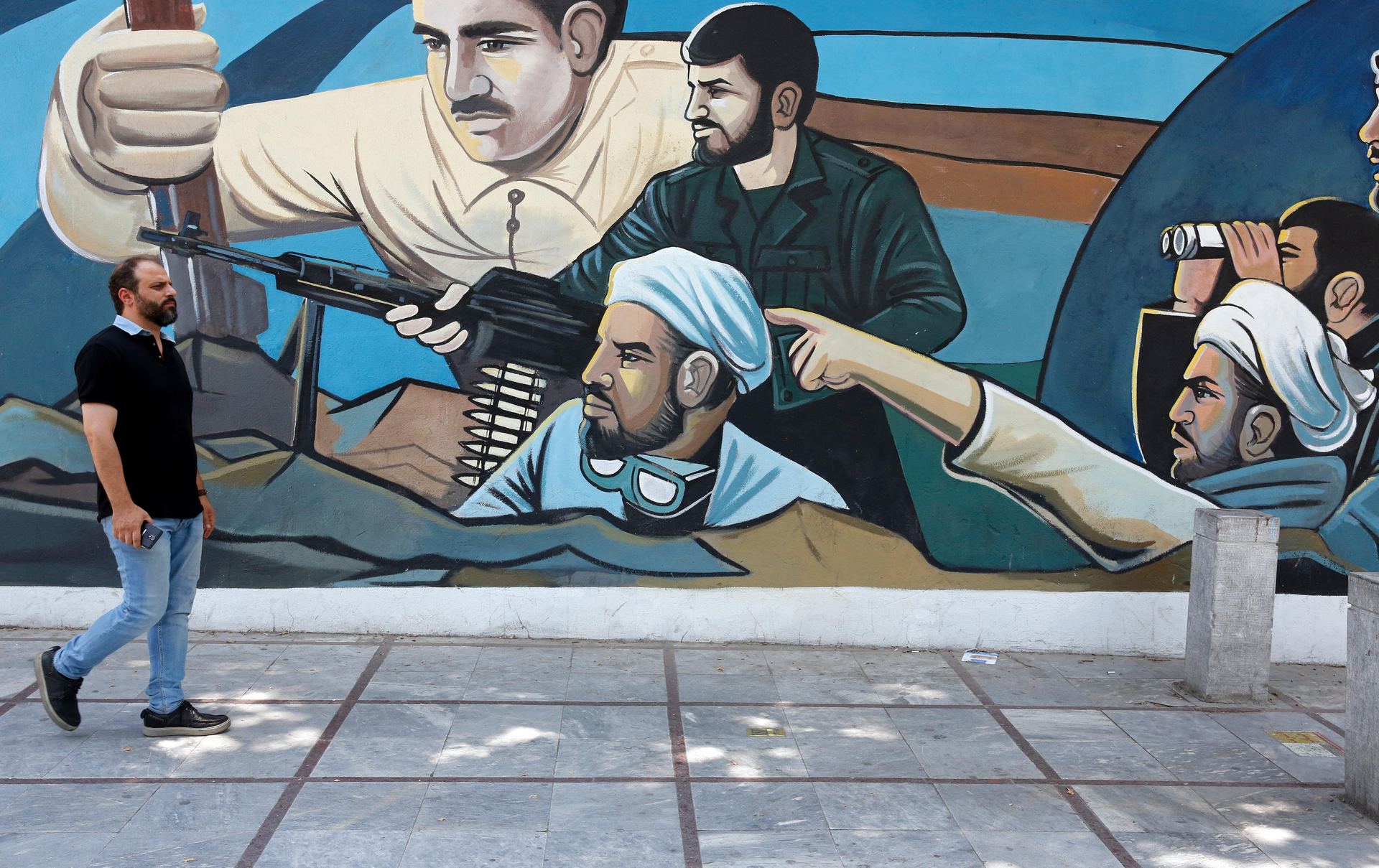 Un iraní camina delante de un mural en una calle de la capital de Irán, Teherán. / EFE