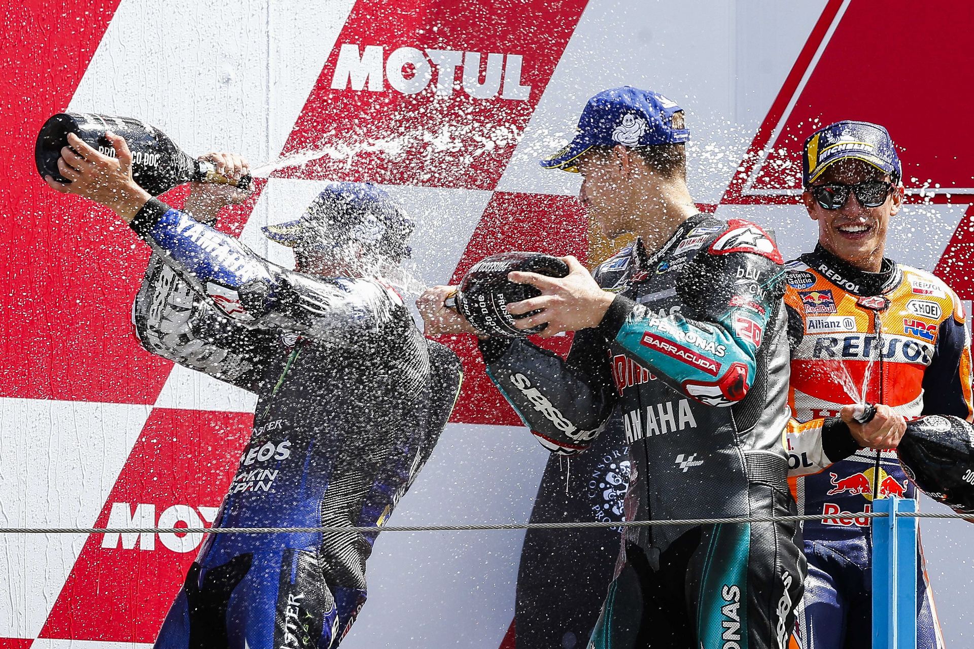 El ganador del GP de Aspen, Maverick Viñales, celebra su victoria con Fabio Quartararo (i) y Marc Márquez (d).