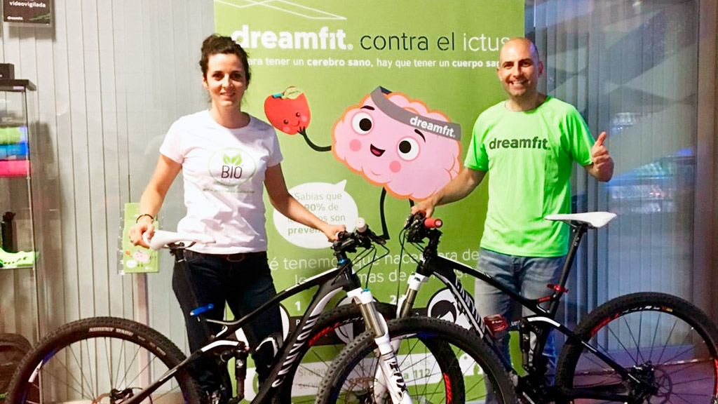 Irene y Pachi, con sus bicicletas, posan econ el cartel de la iniciativa solidaria en la que colaborarán./ EL ADELANTADO
