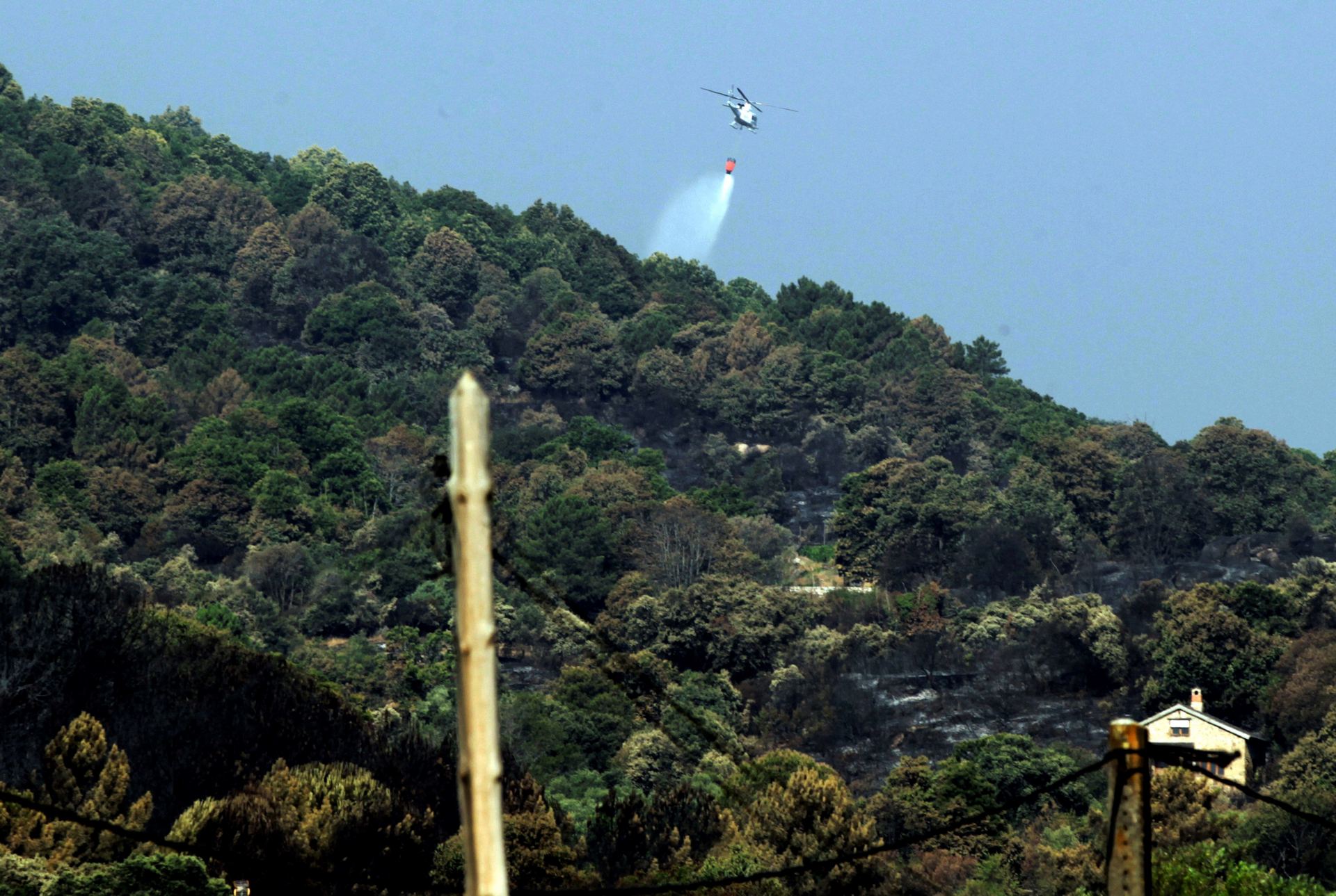 Un helicóptero de Bomberos de Madrid arroja agua en el término municipal de Cadalso de los Ríos.