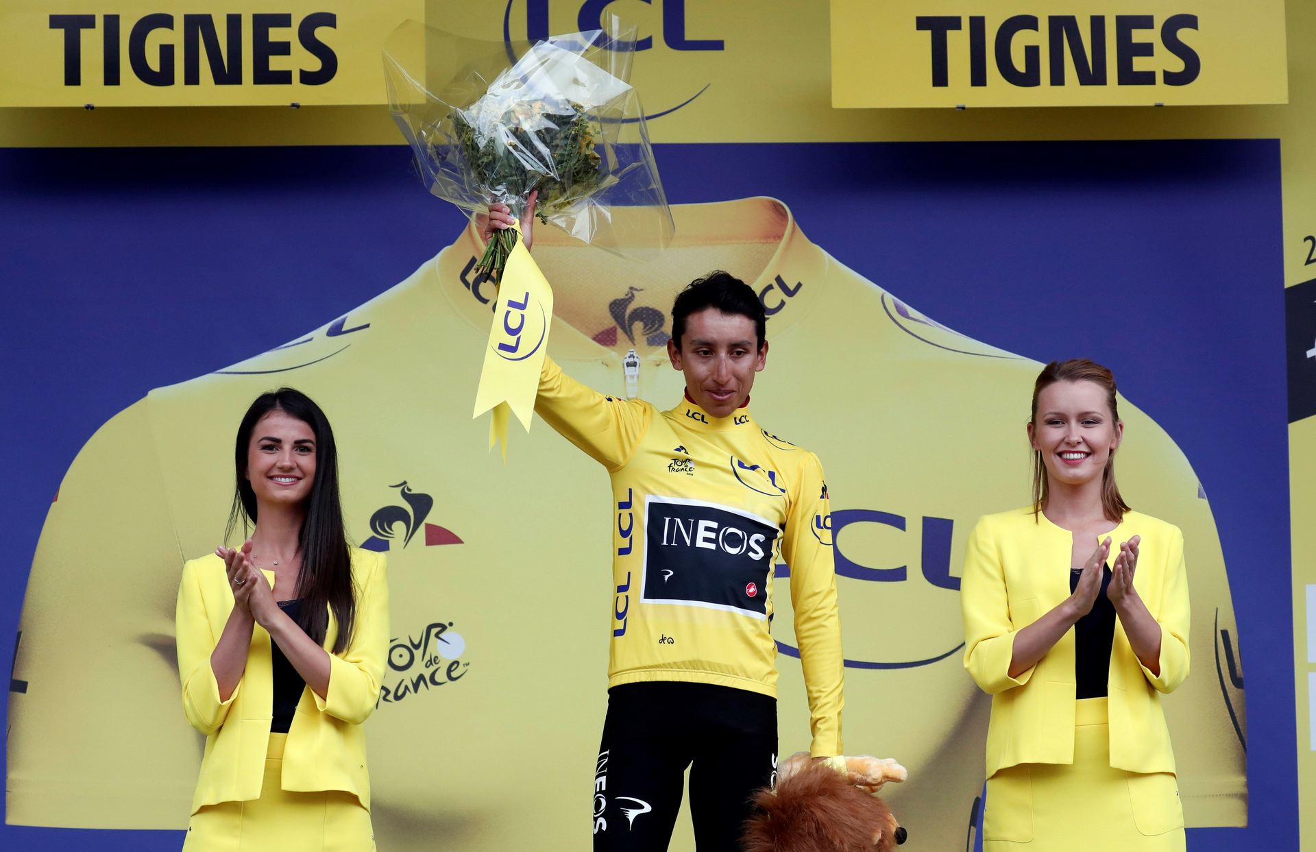 El colombiano Egan Bernal celebra en el podio vestido del maillot amarillo tras una malograda etapa por el granizo.