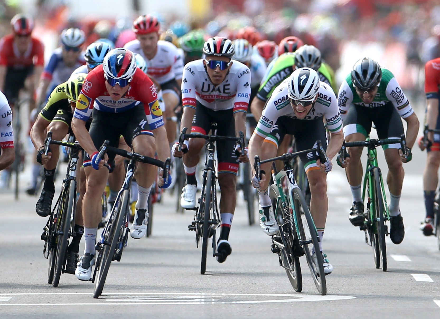 El neerlandés Fabio Jakobsen (izq) se impone en una ajustadísima llegada al esprint al irlandés Sam Bennett (dcha). / EFE