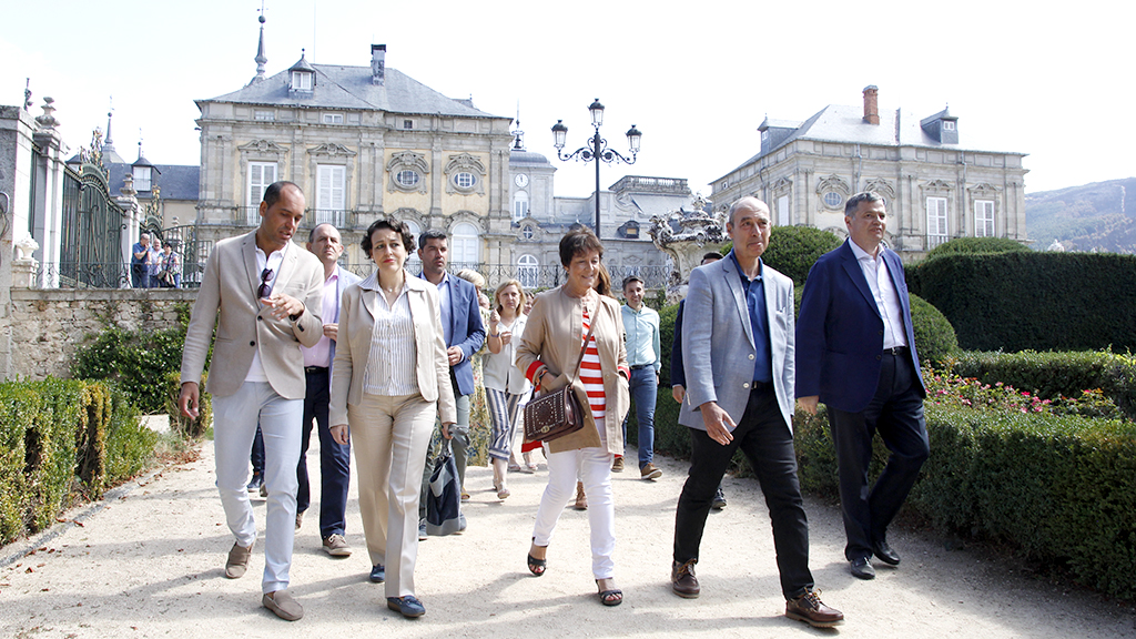 La ministra de Trabajo en funciones, a la izquierda con el alcalde del Real Sitio Samuel Alonso, se dirigió a la Escuela Taller cruzando por los jardines del Palacio Real./NEREA LLORENTE