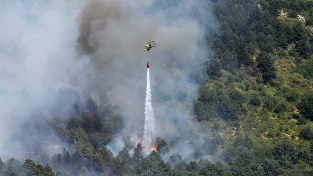 Un helicóptero descarga agua en uno de los puntos del incendio forestal activo desde primera hora de la tarde en La Granja. / Rocío Pardos