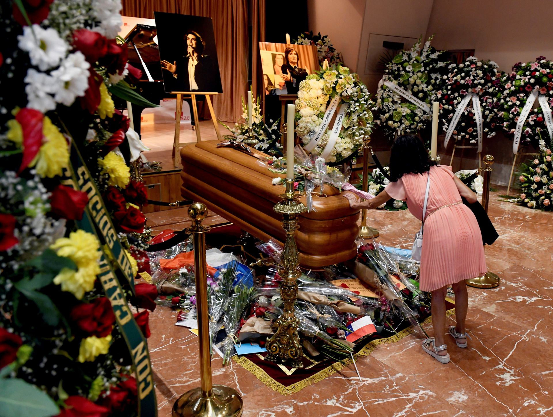 Una mujer deposita flores ante el féretro de Camilo Sesto, en la capilla ardiente habilitada en la sede de la SGAE.