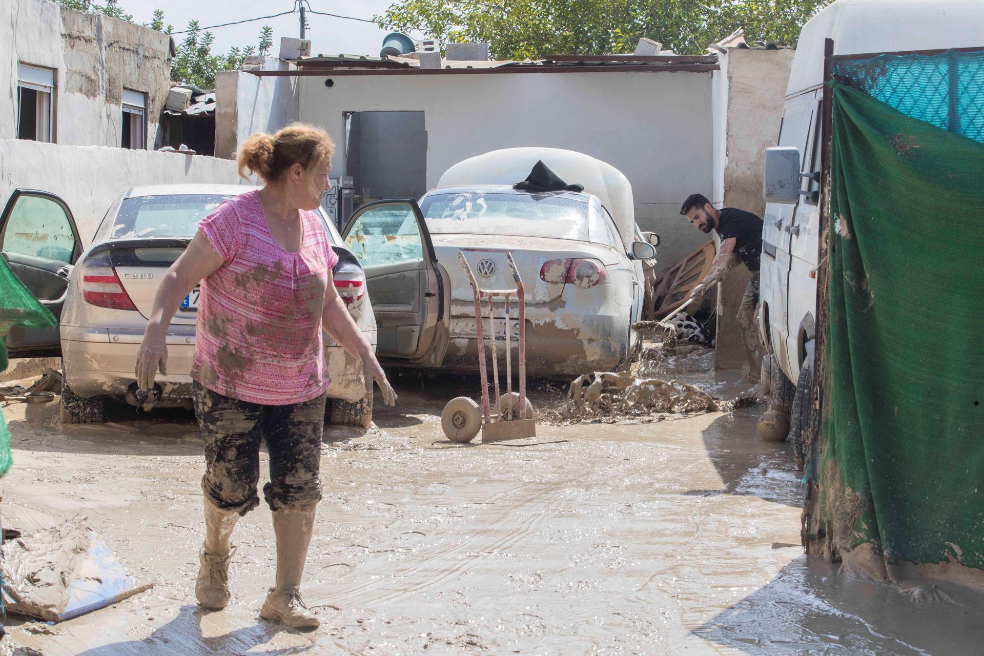 Unos vecinos de Molina de Segura arrastran el lodo depositado en su vivienda tras las últimas inundaciones. / efe