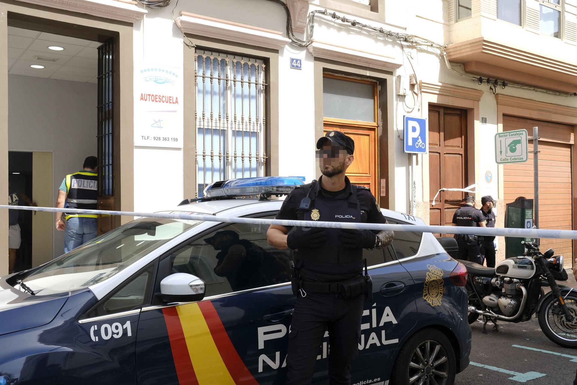 Un policía vigila la entrada del edificio donde un hombre ha asesinado a su expareja para suicidarse después.