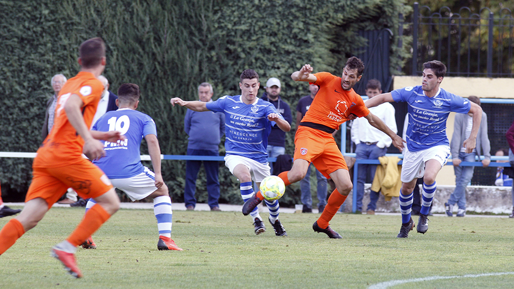 Los jugadores del CD La Granja David Moreno y Kike disputan un balón con un componente del Burgos Promesas 2.000. / NEREA LLORENTE